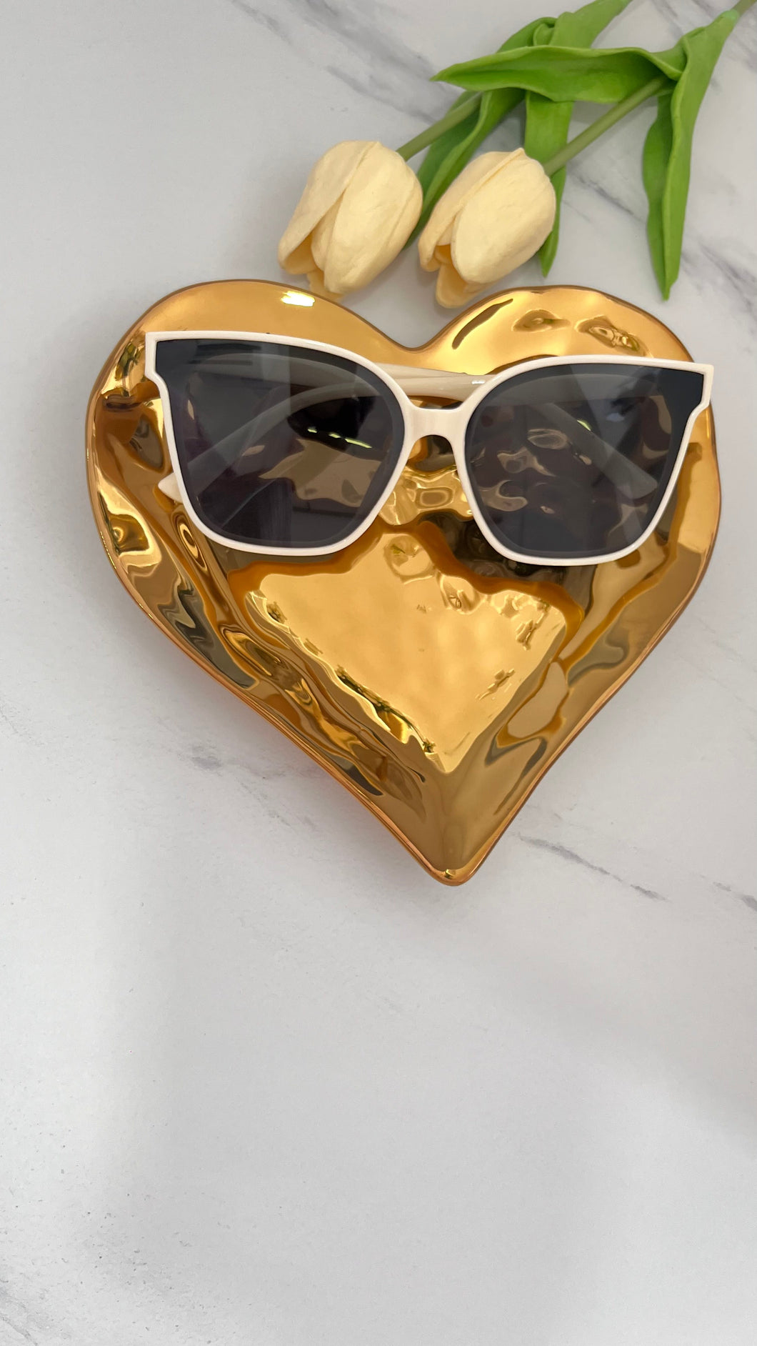 Beige MT Sunnies displayed on a golden heart tray with fresh tulips, showcasing quality jewelry accessories.